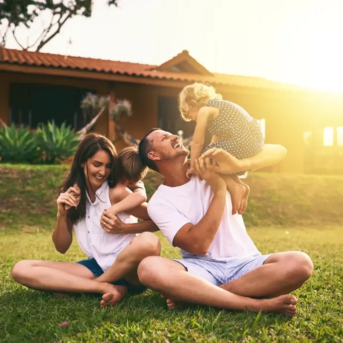 Madre y padre jugando con sus dos hijos pequeños en el jardín de su casa
